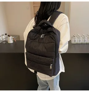 Detail of black puffer backpack with quilted fabric and silver zipper closure for commuting