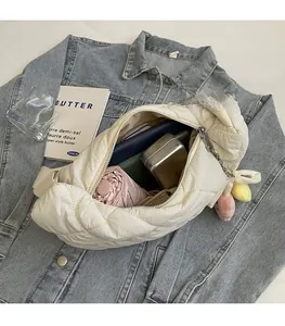 Platliggende weergave van de ruime binnenkant van een witte gewatteerde crossbodytas met spullen
