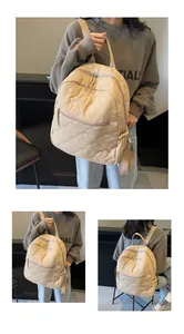 Close-up of beige quilted backpack with bow embroidery and adjustable shoulder straps
