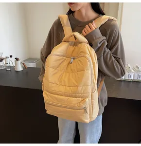 Detail of yellow quilted puffer backpack with front zipper pocket and side sleeve