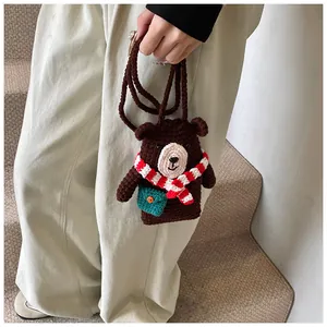 Detail of handmade knit bear shoulder bag with striped scarf and green front pocket