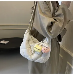 Detail van witte gewatteerde puffer tas met pluche harthanger op kaki trenchcoat
