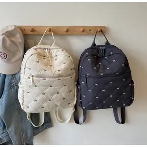 Detailed quilted texture of backpack showing butterfly embroidery and zipper pocket