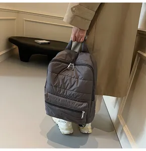 Close-up of charcoal grey quilted backpack featuring puffer style texture and silver zippers