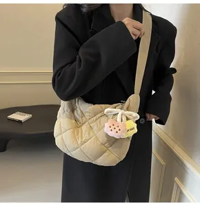 Detail van beige gewatteerde halve maan schoudertas met pluche hanger op een model
