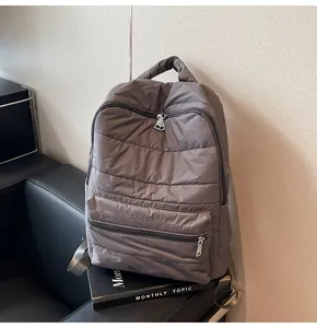 Detail of grey quilted backpack showing padded fabric and durable zipper compartments