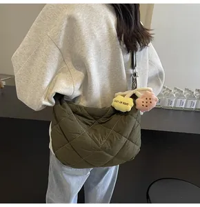 Detail van de legergroene gewatteerde crossbodytas met een pluchen gele bloemenhanger