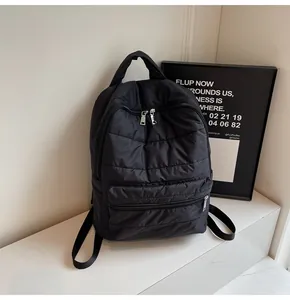 Detail of black quilted puffer backpack with top handle and adjustable fabric straps
