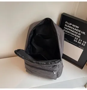 Internal view of dark grey quilted backpack showing spacious main pocket and zipped pocket