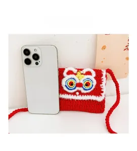 Detailed size comparison of mini handmade crochet lion dance bag with a smartphone