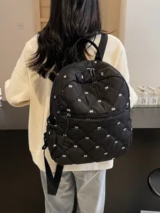 Quilted black backpack with white bow embroidery and adjustable shoulder straps