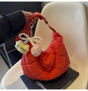 Detail van de oranje gewatteerde crossbodytas met pluche hanger en zilveren gespen