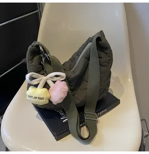 Detail van olijfgroene gewatteerde schoudertas met kersenhanger en verstelbare riem