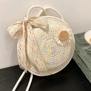 Round bohemian woven straw bag in creamy white with colorful wavy stitching and a lace bow