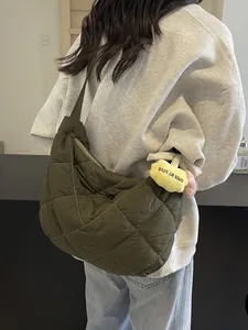 Olijfgroene gewatteerde puffer schoudertas met gele pluchen bloemhanger bij model