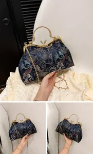 Close-up of blue embroidered shell bag with floral patterns and butterfly clasp