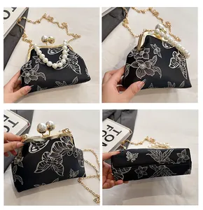 Detalles de bordado floral, asas de perlas y cadena dorada en el bolso de concha