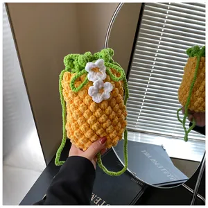 Detail of handmade knit pineapple pouch featuring yellow texture and green leaf drawstring