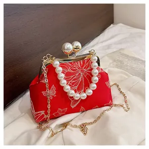 Detalle de bolso de satén rojo con bordado de mariposa y cierre de perlas grandes