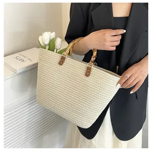 Detail of bamboo handles with leather trim and gold rings on a straw tote bag