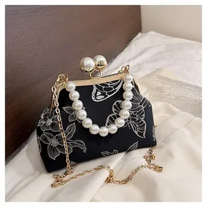 Detalle macro del bolso bordado chino con cierre de perla y motivos florales retro