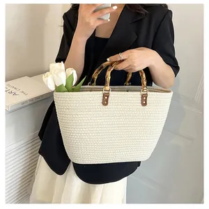 Detail showing the natural bamboo handles and handwoven texture of the beige straw tote bag