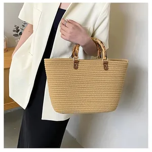 Close-up of woven straw tote bag featuring iconic bamboo top handles and vintage metal hardware