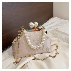 Detalle del bordado floral y asa de perlas en un bolso vintage elegante