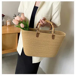 Detail of the woven straw tote bag featuring natural bamboo handles and leather accents