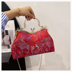 Detail of red brocade shell bag with butterfly clasp and rhinestone handle