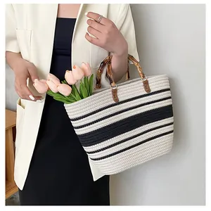 Detail of handwoven black and white striped tote bag with natural bamboo handles