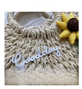 Detail of beige woven straw bag with sunflower and Good Day embroidery detail