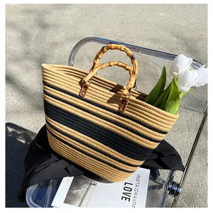 Detail of woven straw tote bag with bamboo handles and black stripes on a chair