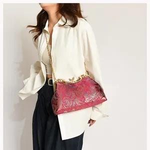 Detail of red satin shell bag with traditional floral embroidery and gold chain strap