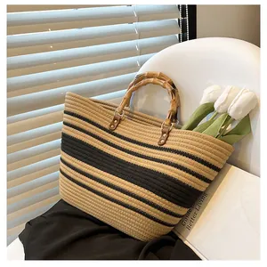 Detail of hand-woven straw tote with black stripes and natural bamboo handles for beach