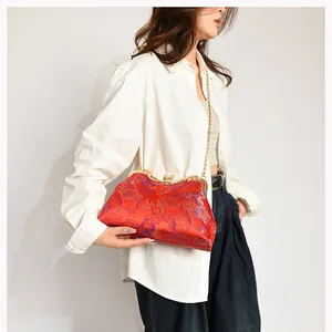 Detail view of red silk shell bag with traditional Chinese embroidery and gold chain