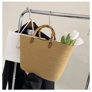 Detail of hand-woven straw tote bag with bamboo handle and premium leather connector