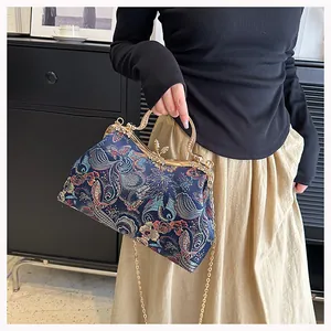 Close-up of brocade shell bag with floral butterfly embroidery and rhinestone handle
