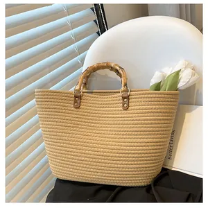 Detail of hand-woven straw tote with bamboo U-handles and elegant golden rivets