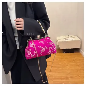Detailed close-up of cherry blossom embroidery and pearl clasp on the pink satin handbag