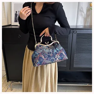 Detailed shot of dark blue brocade bag with floral patterns and gold chain strap