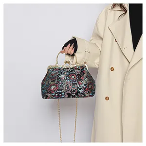 Macro detail of floral embroidery and metallic frame lock on a vintage style handbag