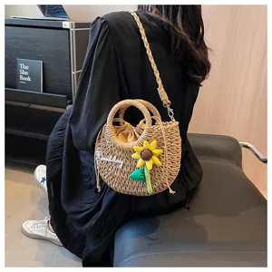 Detail of straw woven bag with Goodday embroidery and sunflower charm for summer holidays