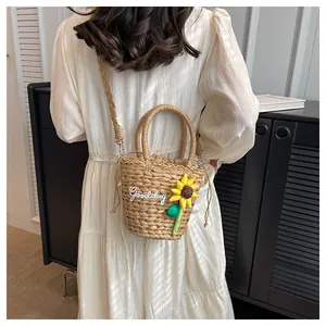 Detailed close-up of straw bucket bag with sunflower charm and Goodday embroidery