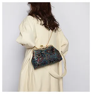 Detail of vintage navy blue brocade frame bag with floral embroidery and gold chain strap