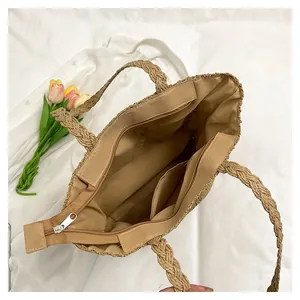 Detail of straw tote bag interior showing zipper closure, inner pockets and braided handles