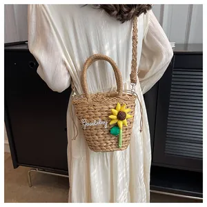 Detail of hand-woven straw bucket bag with sunflower applique and Goodday embroidery