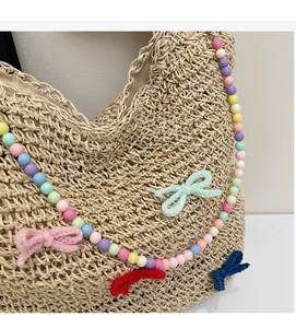 Detailed close-up of hand-woven straw tote with colorful beads and cute bows