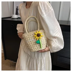 Close-up of woven straw bucket bag with 3D sunflower decor and Goodday embroidery
