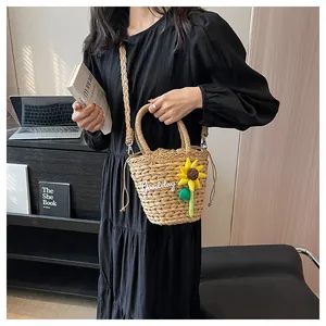 Detail of straw bucket bag with sunflower charm and 'Goodday' embroidery on the woven texture